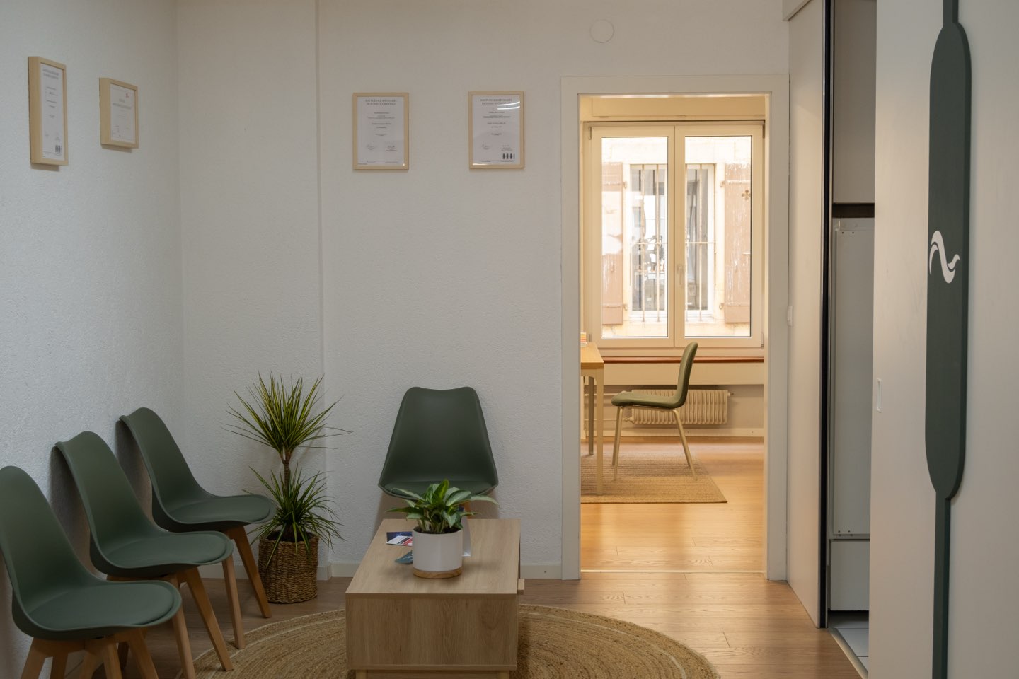 La salle d’attente : chaises vert sauge, table basse et plantes