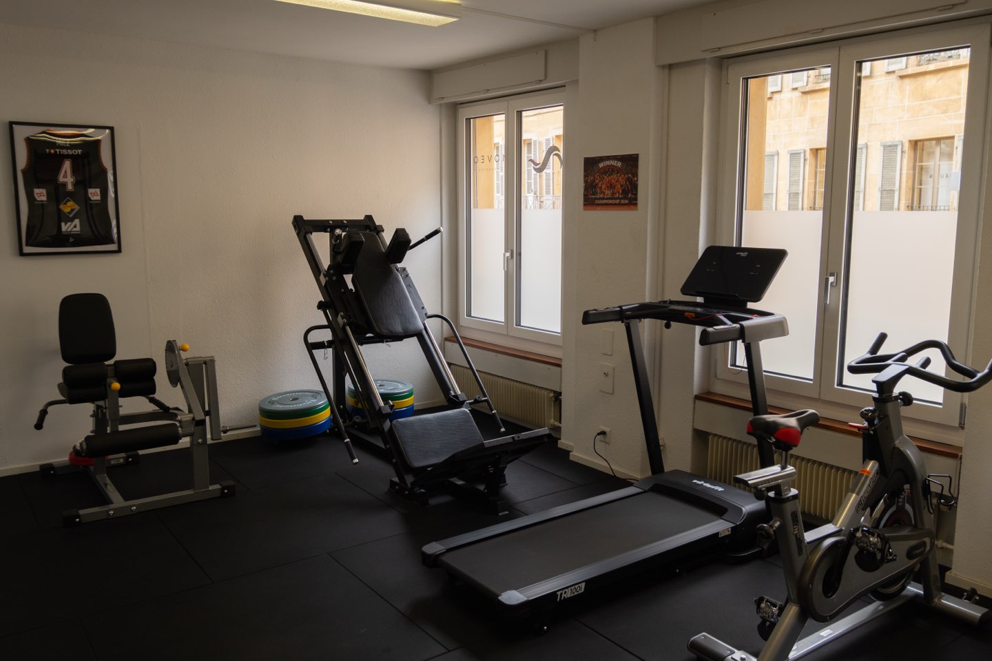 La salle d’entraînement : presse à cuisses, tapis de course et vélo