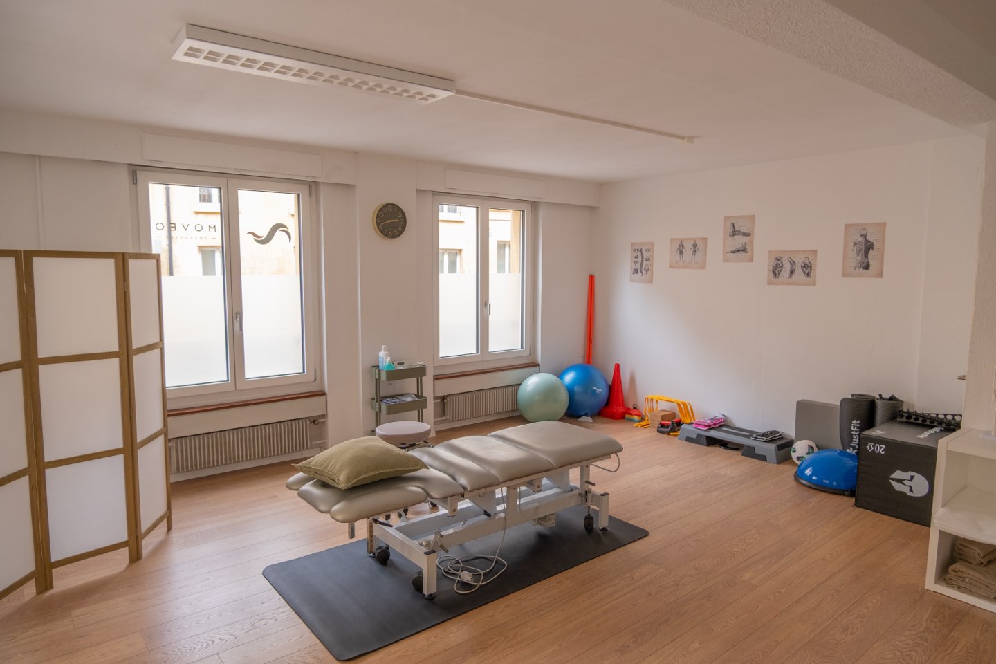 Une salle de traitement lumineuse avec table, ballons et matériel de rééducation